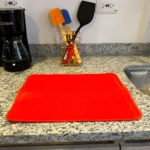 Alfombrilla de silicona roja para secar platos y utensilios en cocina gourmet.