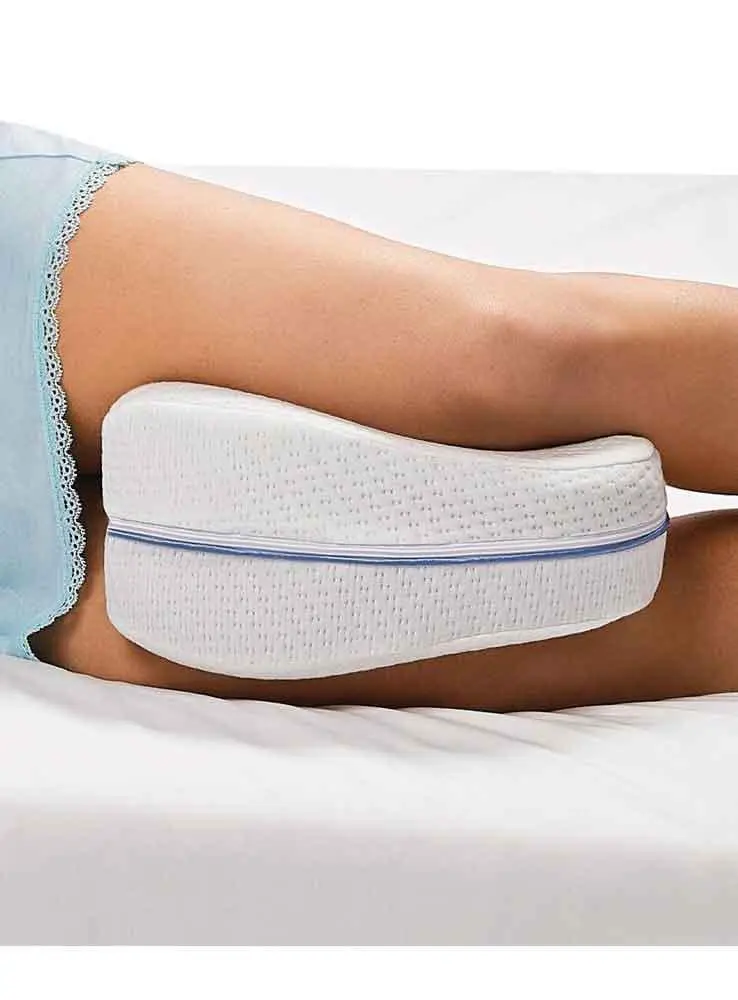 Almohada para piernas Leg Pillow blanca entre las piernas de persona durmiendo de lado.