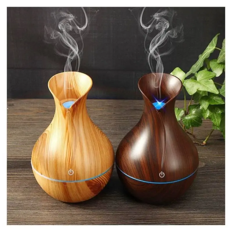 Humidificador difusor de aroma en forma de jarrón de madera clara y oscura con vapor.