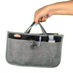 Organizador de bolso gris para dama con cepillo, bolígrafo, llaves y desinfectante.