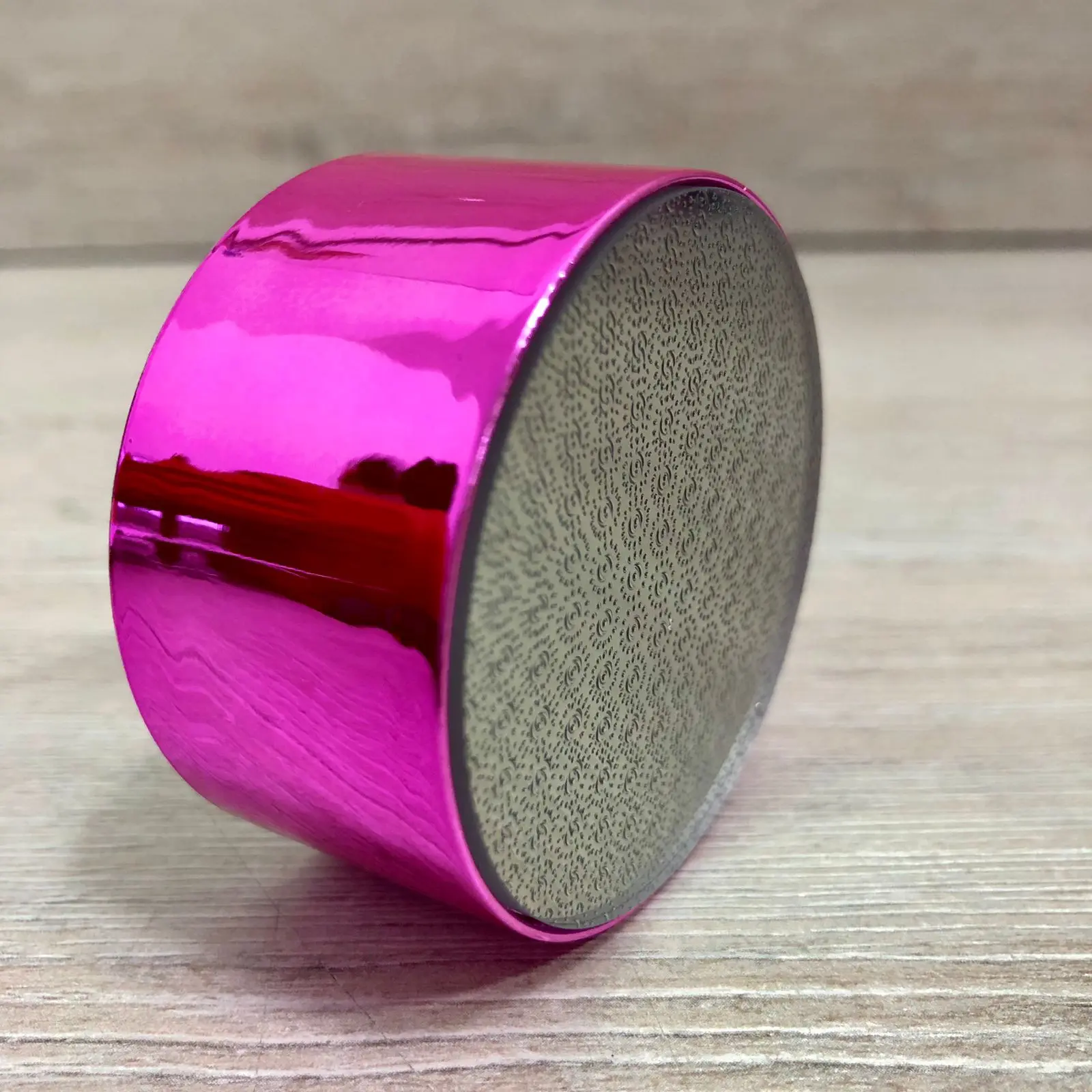 Depilador de cristal y quitacayos rosa metálico en superficie de madera clara.