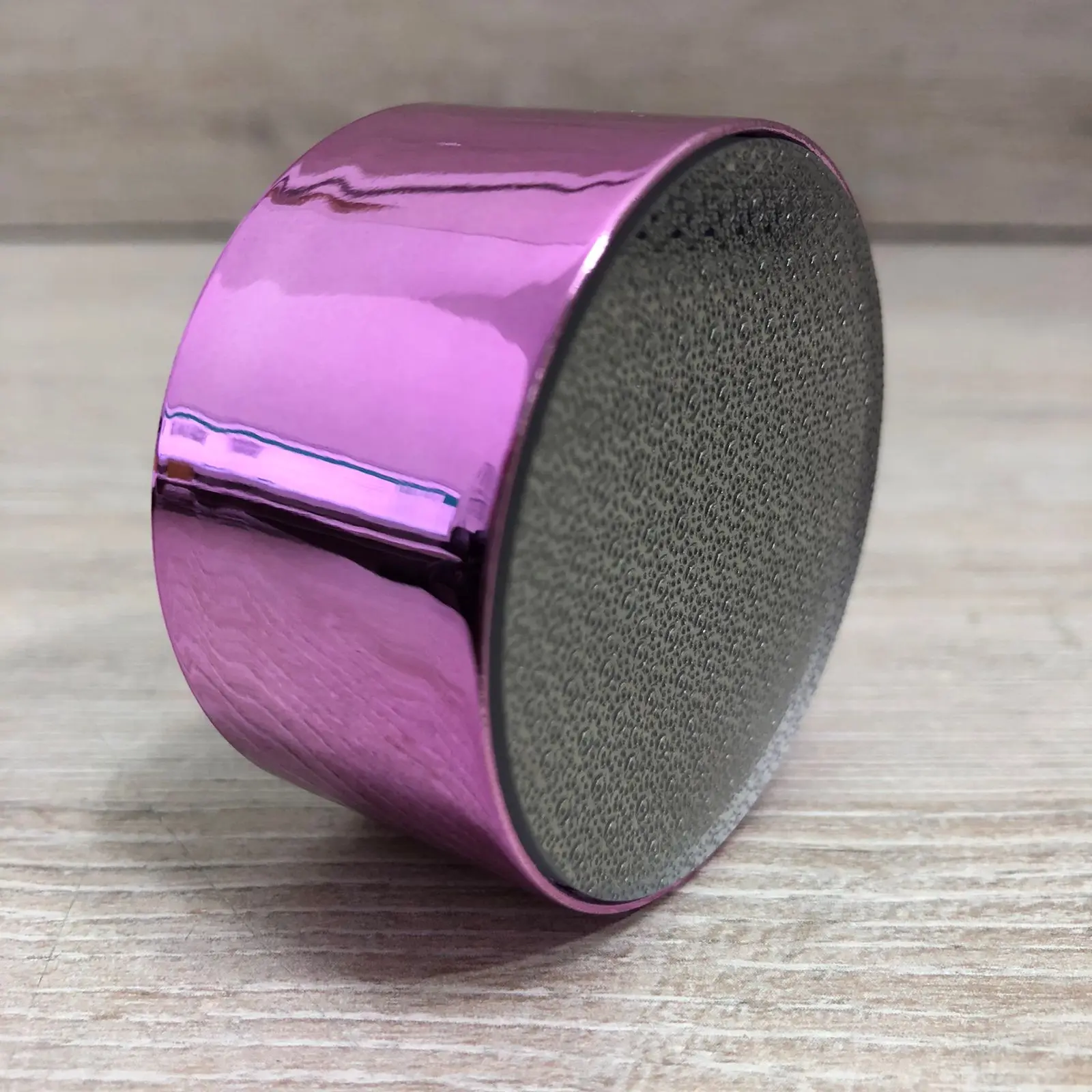 Depilador de cristal rosa brillante con superficie para quitar callos, sobre madera.