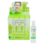 Fijador de Maquillaje Karité BIO Lemongrass en spray con hierba, rostro de modelo y gotas de agua.