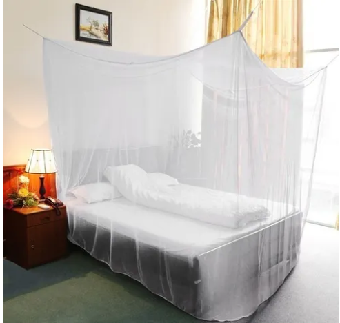 Toldillo mosquitero blanco suspendido sobre cama con sábanas blancas y mesa de noche.