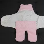 Cobertor de bebé rosa con capota de osito, sobre fondo negro.