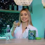Mujer sonriente con un vaso de bebida y un envase de Fibra MW.