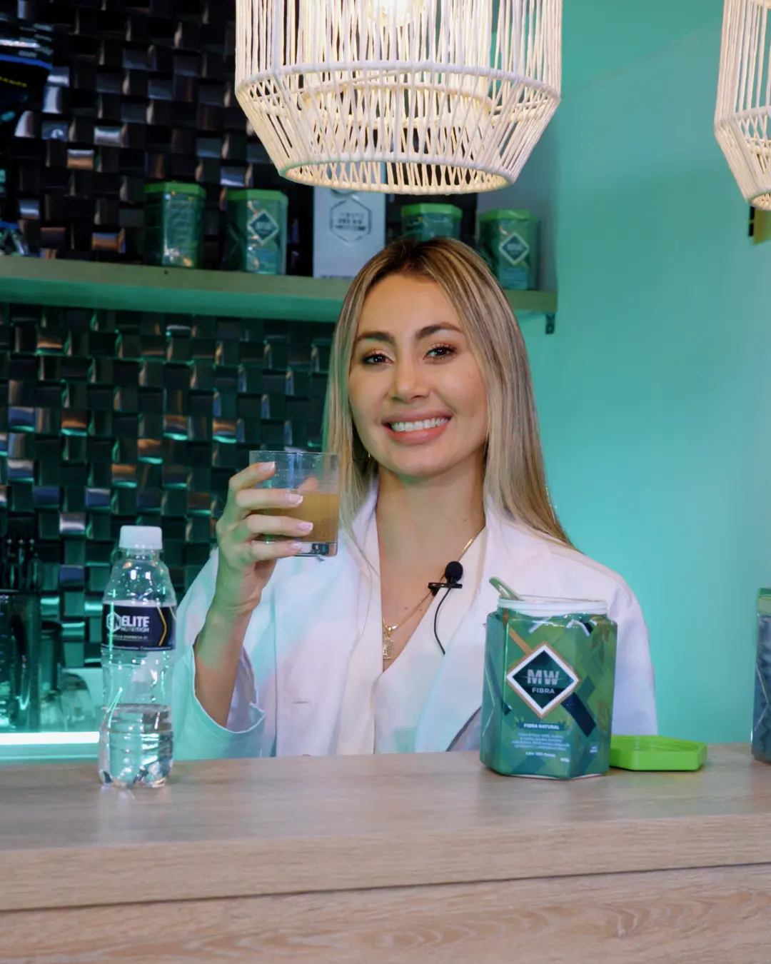 Mujer sonriente con un vaso de bebida y un envase de Fibra MW.