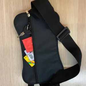 Sujetador para motocicleta negro con llaves y tarjetas expuestas en compartimento con cremallera.