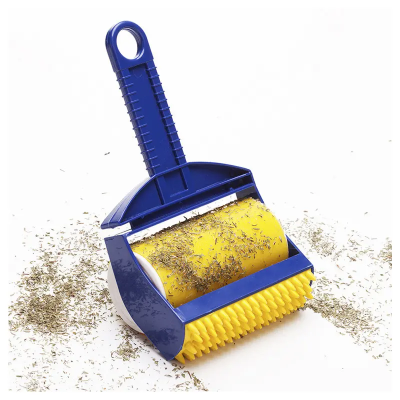 Rodillo quita pelo con adhesivo amarillo y mango azul sobre superficie con residuos de hierba.