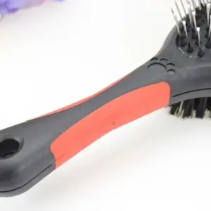 Cepillo para mascotas doble cara con cerdas metálicas y nylon, mango ergonómico rojo y negro.