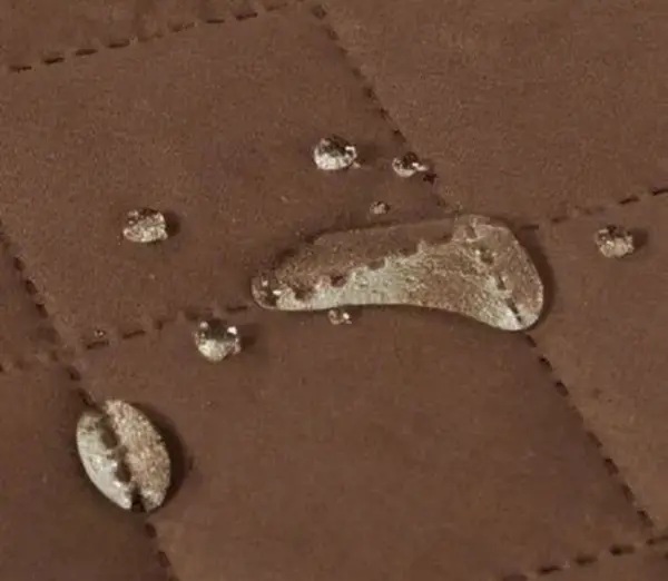 Cubre sofá de 2 puestos marrón con gotas de agua que demuestran su impermeabilidad.