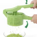 Exprimidor escurridor de cocina verde machacando y escurriendo verduras en un bol de cristal.
