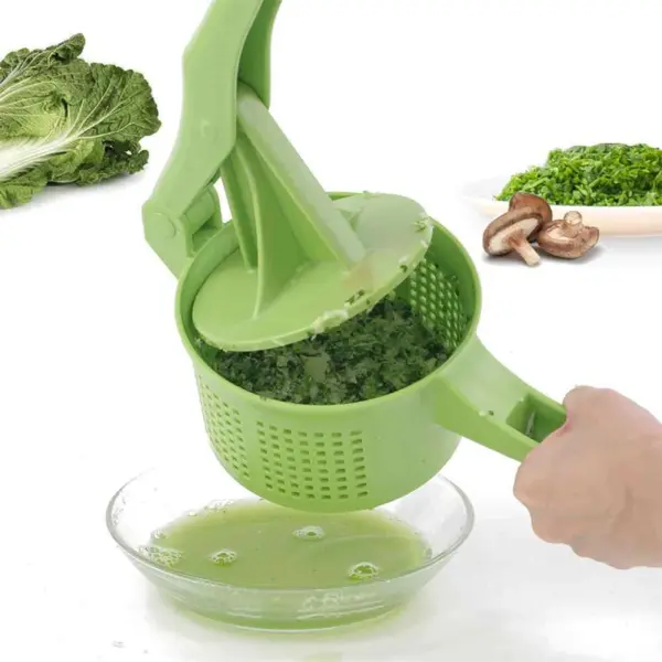 Exprimidor escurridor de cocina verde triturando verduras en un tazón con jugo verde.