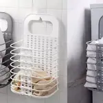 Cesta plegable multiusos gris con ropa blanca para colgar en pared.