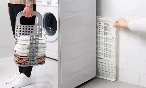 Cesta plegable multiusos gris para ropa, junto a lavadora y cesta blanca expandida.