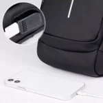 Canguro antirrobo negro con puerto USB externo cargando un teléfono blanco.