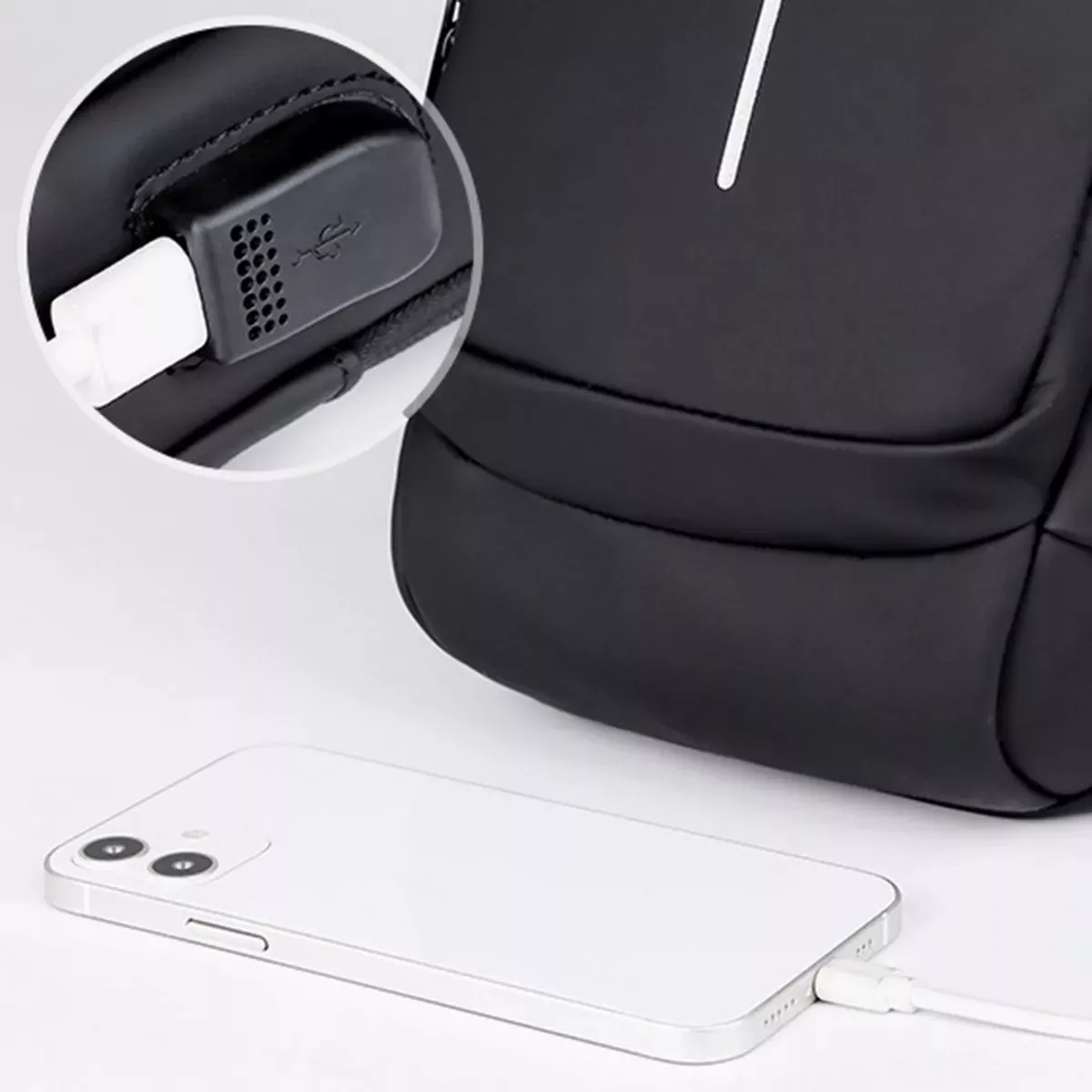 Canguro antirrobo negro con puerto USB externo cargando un teléfono blanco.