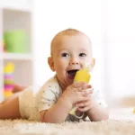 Bebé feliz en el suelo jugando con cuchara biberón de papillas para bebé