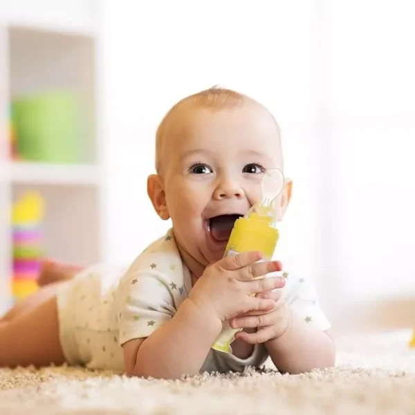 Bebé feliz en el suelo jugando con cuchara biberón de papillas para bebé