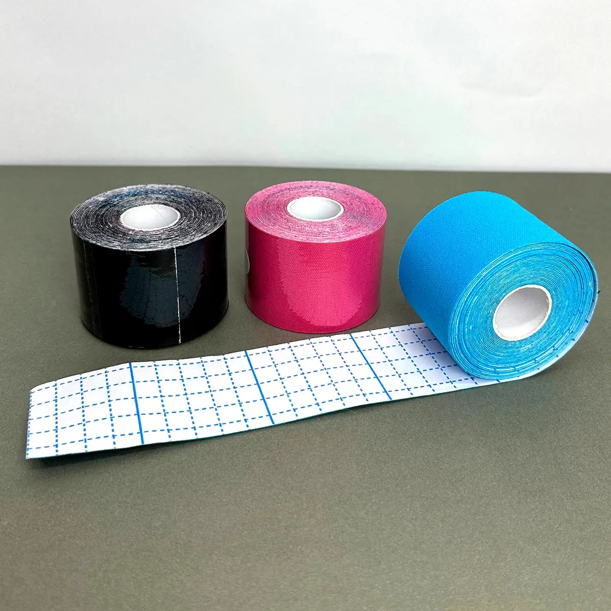 Cintas kinesiológicas neuromusculares: negra, fucsia y azul. Cinta con cuadrícula para corte.