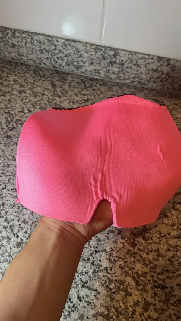 Gorro relajante para migraña rosa, sujeto en mano, cubriendo la parte superior de una encimera.