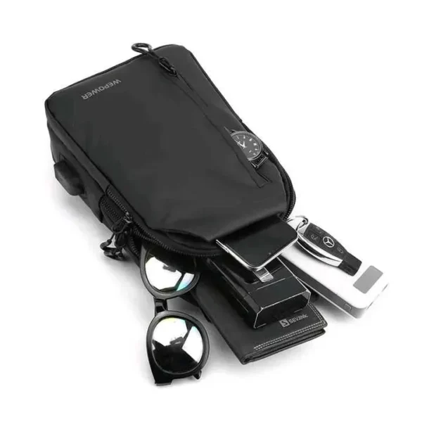 Bolso pechero negro con smartphone, cartera, gafas de sol y llaves de coche.