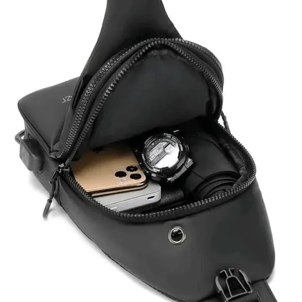 Bolso pechero negro con celular dorado, reloj deportivo y paraguas enrollado en su interior.