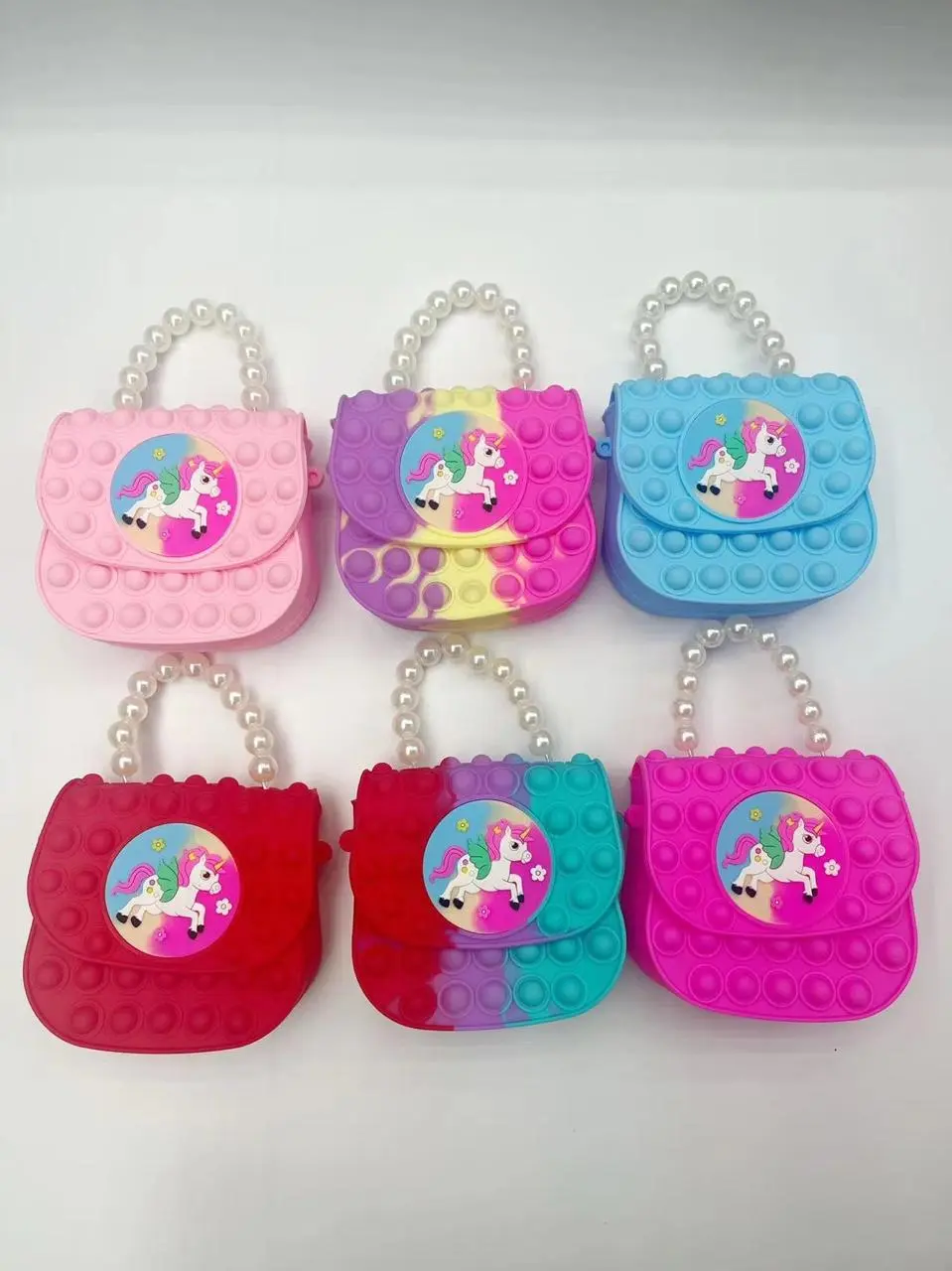 Bolso pop it rosa y morado para niña con diseño de unicornio y perlas.