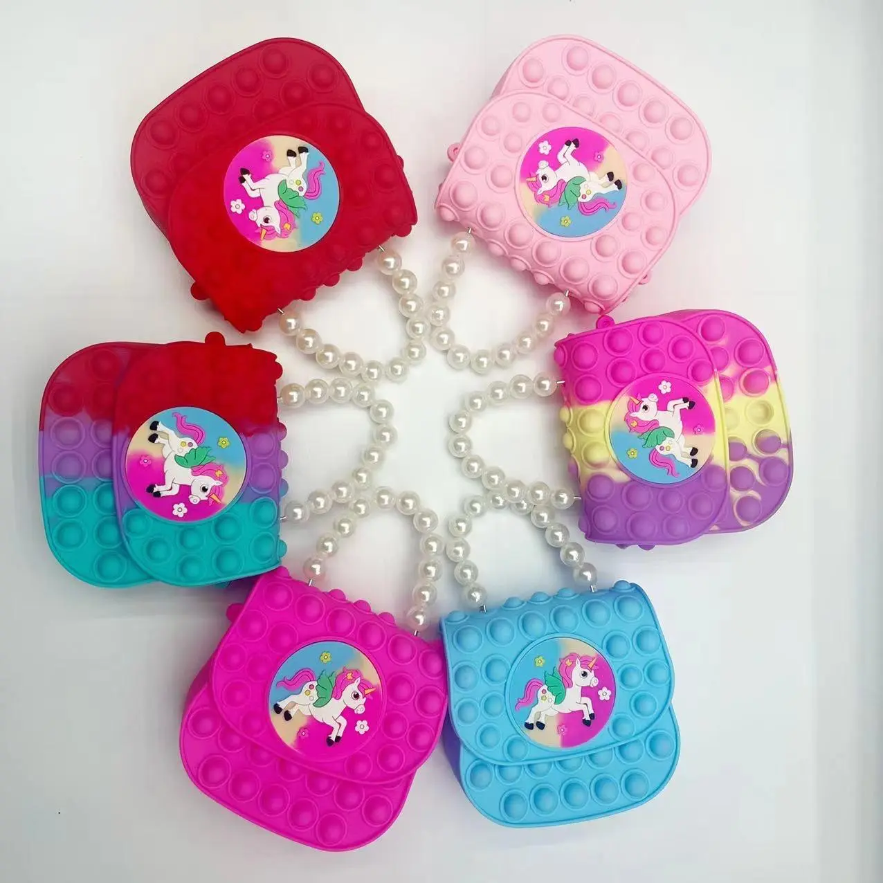 Bolso pop it para niña con diseño de unicornio, disponible en varios colores vibrantes.