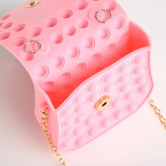 Bolso rosa para niña estilo Pop It con cadena dorada y broche de metal.