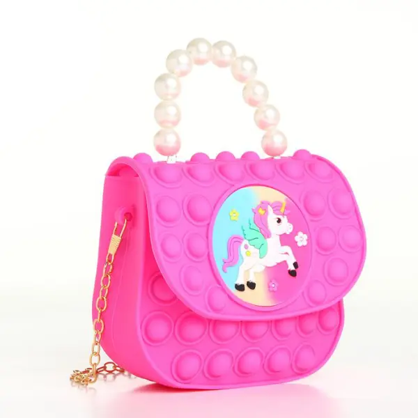 Bolso para niña color fucsia estilo Pop It con diseño de unicornio y asa de perlas.