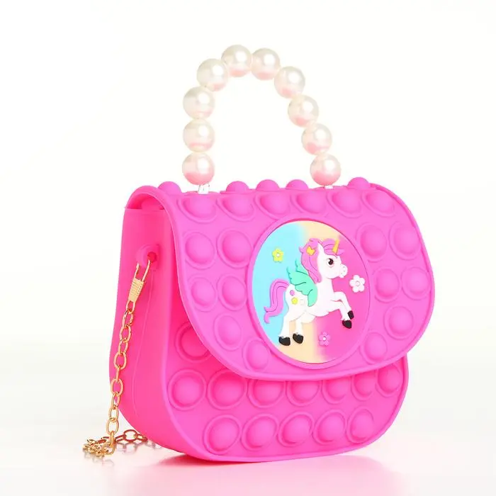 Bolso para niña color fucsia estilo Pop It con diseño de unicornio y asa de perlas.