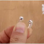 Combo de 2 clips nasales para dormir con puntas plateadas, sostenidos por un dedo.