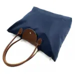 Bolso cartera plegable azul marino con detalles en cuero marrón y cosmetiquera.