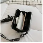 Mini bolso plateado con correa negra "Forever Young", abierto con móvil y libreta dentro.