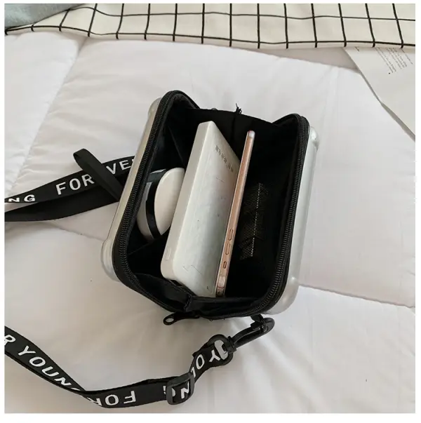 Mini bolso plateado con correa negra "Forever Young", abierto con móvil y libreta dentro.