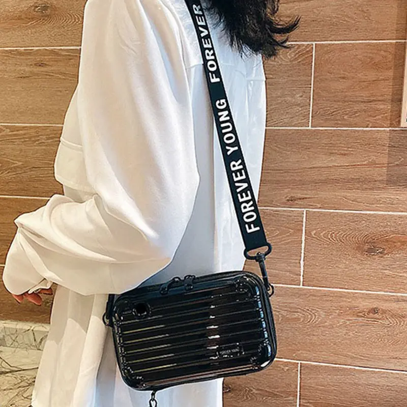 Mini bolso negro brillante con correa de tela "Forever Young" cruzado al hombro.