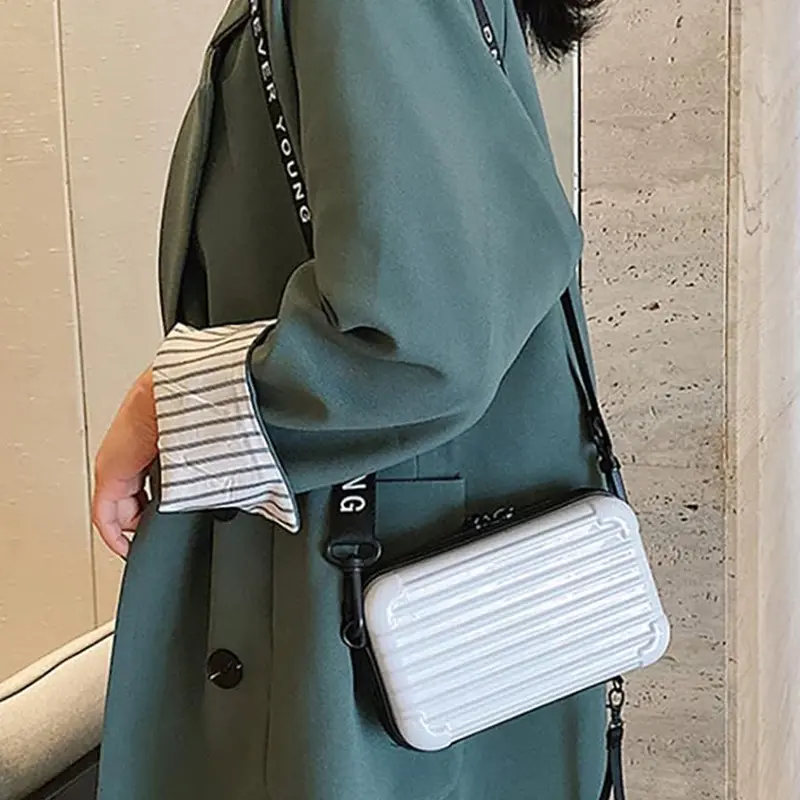 Mini bolso blanco tipo maleta con correa de tela con texto, estilo moderno.