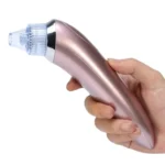 Extractor de puntos negros y espinillas en tono rosa sostenido por una mano.