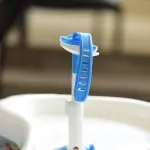 Porta teteros para bebés azul y blanco con ajuste, ideal para mantener el biberón seguro.
