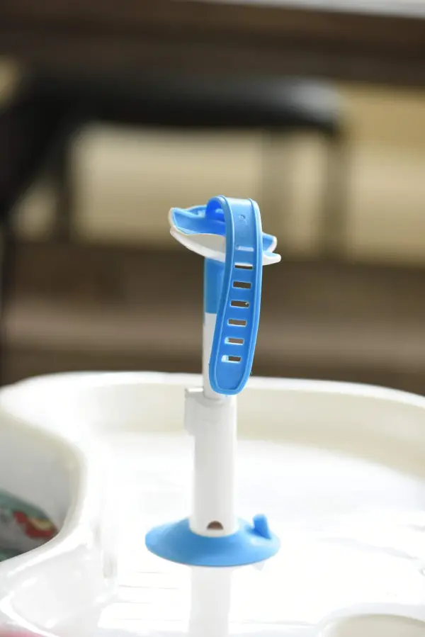 Porta teteros para bebés azul y blanco con ajuste, ideal para mantener el biberón seguro.
