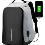 Morral antirrobo gris y negro con puerto USB cargando celular, diseño moderno y seguro.