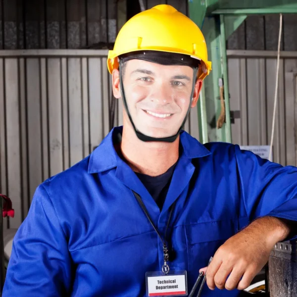 Hombre con casco amarillo y uniforme azul, usando mascarilla protectora facial.