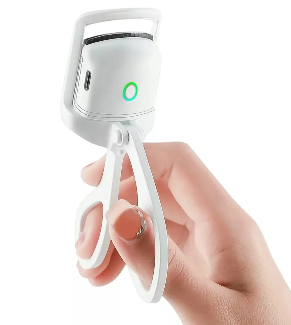 Rizador de pestañas eléctrico blanco sostenido por una mano, con círculo verde encendido.