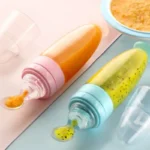 Cuchara biberón con papilla de frutas para bebé, ideal para alimentación complementaria.