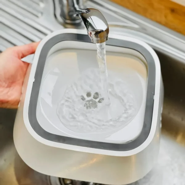 Bebedero antiderrames para mascotas llenándose de agua con huella de pata en el centro.