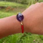 Pulsera con piedra amatista y cordón rojo para limpieza y recarga energética.