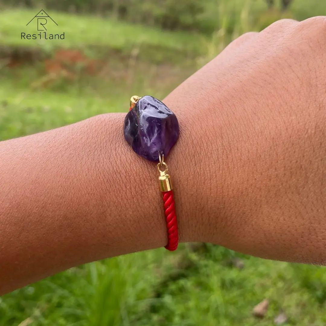 Pulsera con piedra amatista y cordón rojo para limpieza y recarga energética.