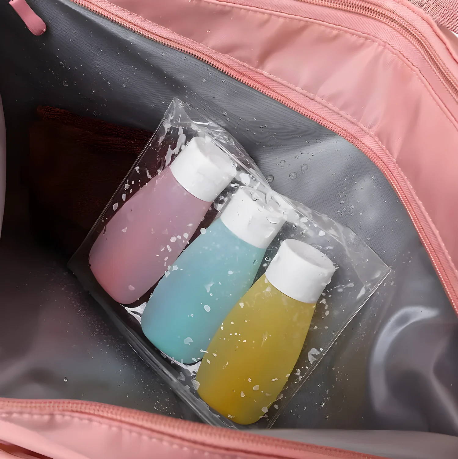 Bolso de viaje impermeable rosado con tres frascos de loción de colores en su interior.