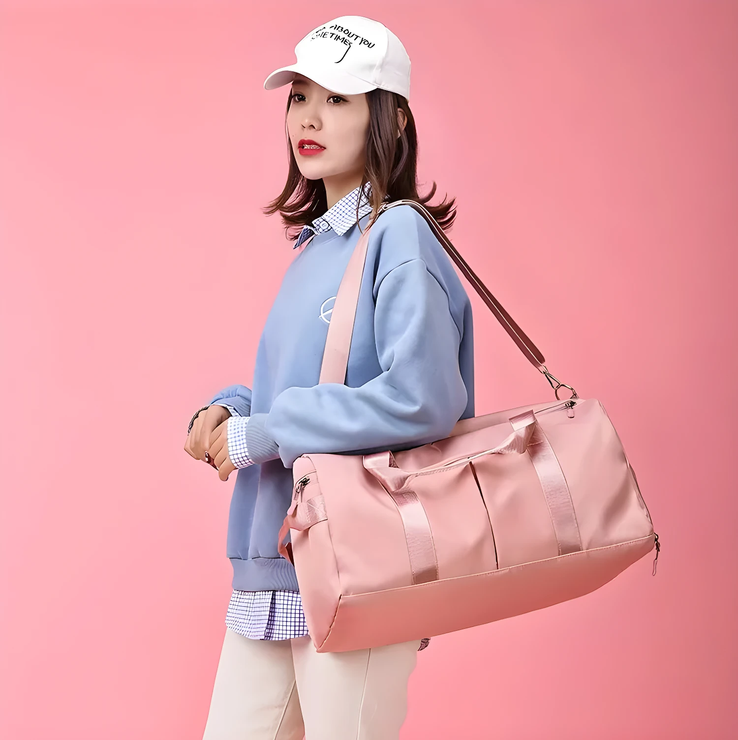 Bolso de viaje o gym impermeable rosa, llevado por mujer con gorra blanca, sobre fondo rosa.
